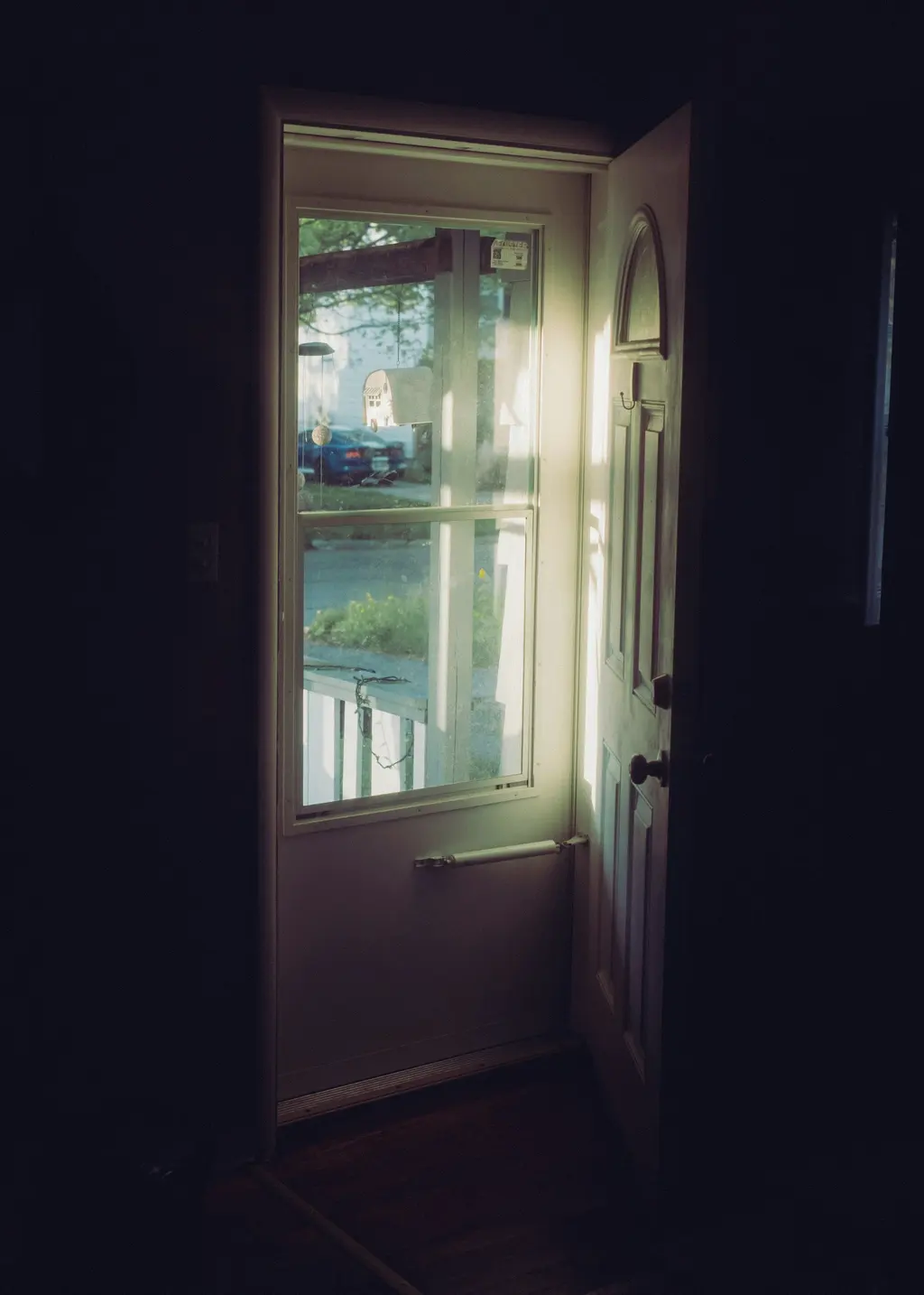 Daylight coming through an open front door into a dark hallway
