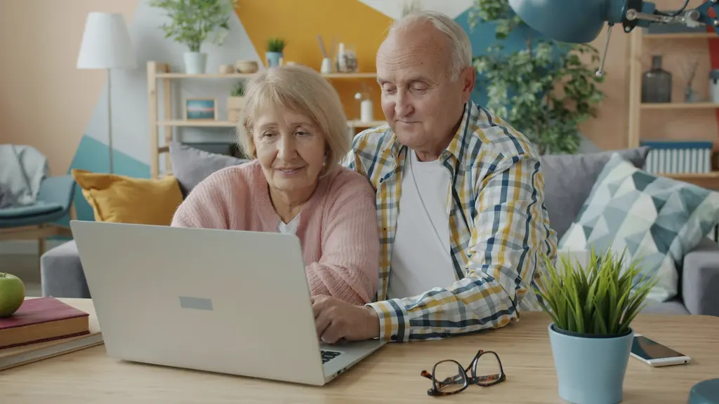 An older couple smiling at a laptop together
