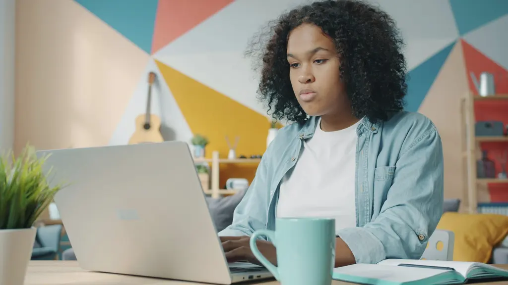 A young woman studying on a laptop at home