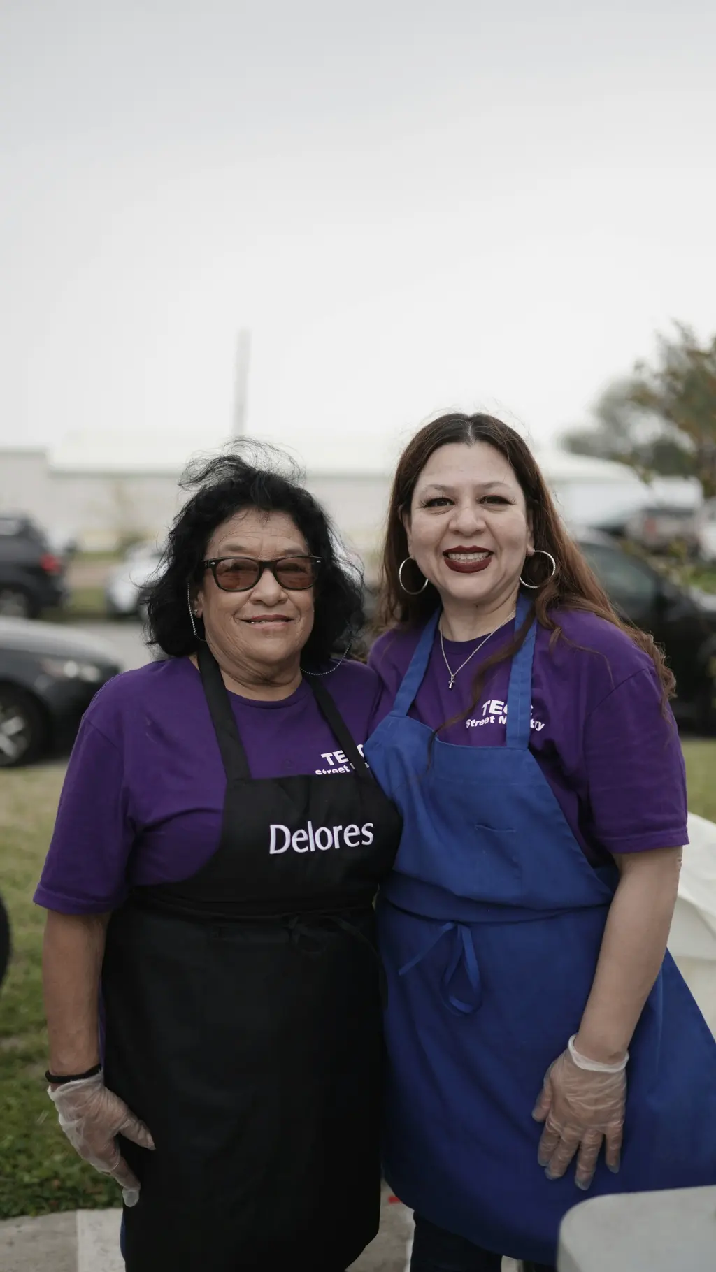Two smiling volunteers in matching aprons